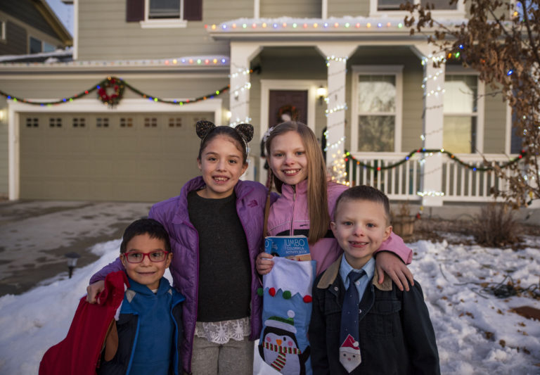 Four young children smile in a snowy front yard