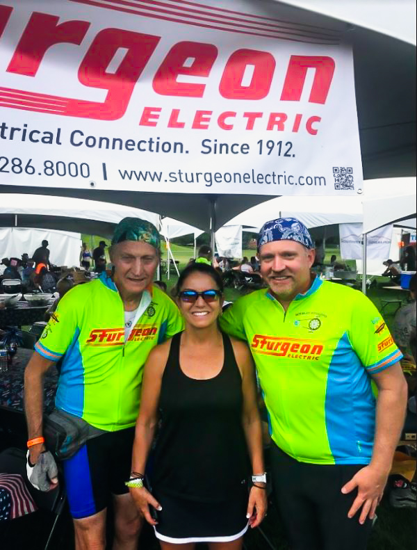 Two men in cycling clothing and a woman looking into the camera