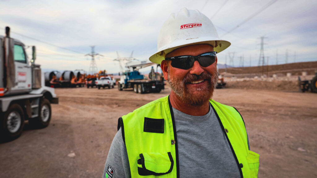A male, Sturgeon Electric worker wearing a hard hat and protective glasses
