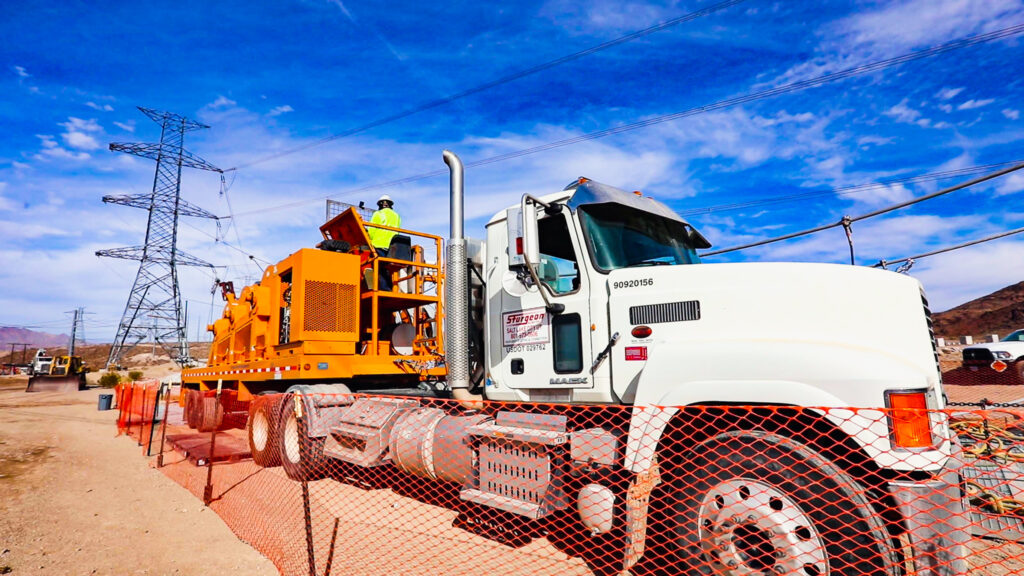 A large construction vehicle with Sturgeon Electric logos under power lines