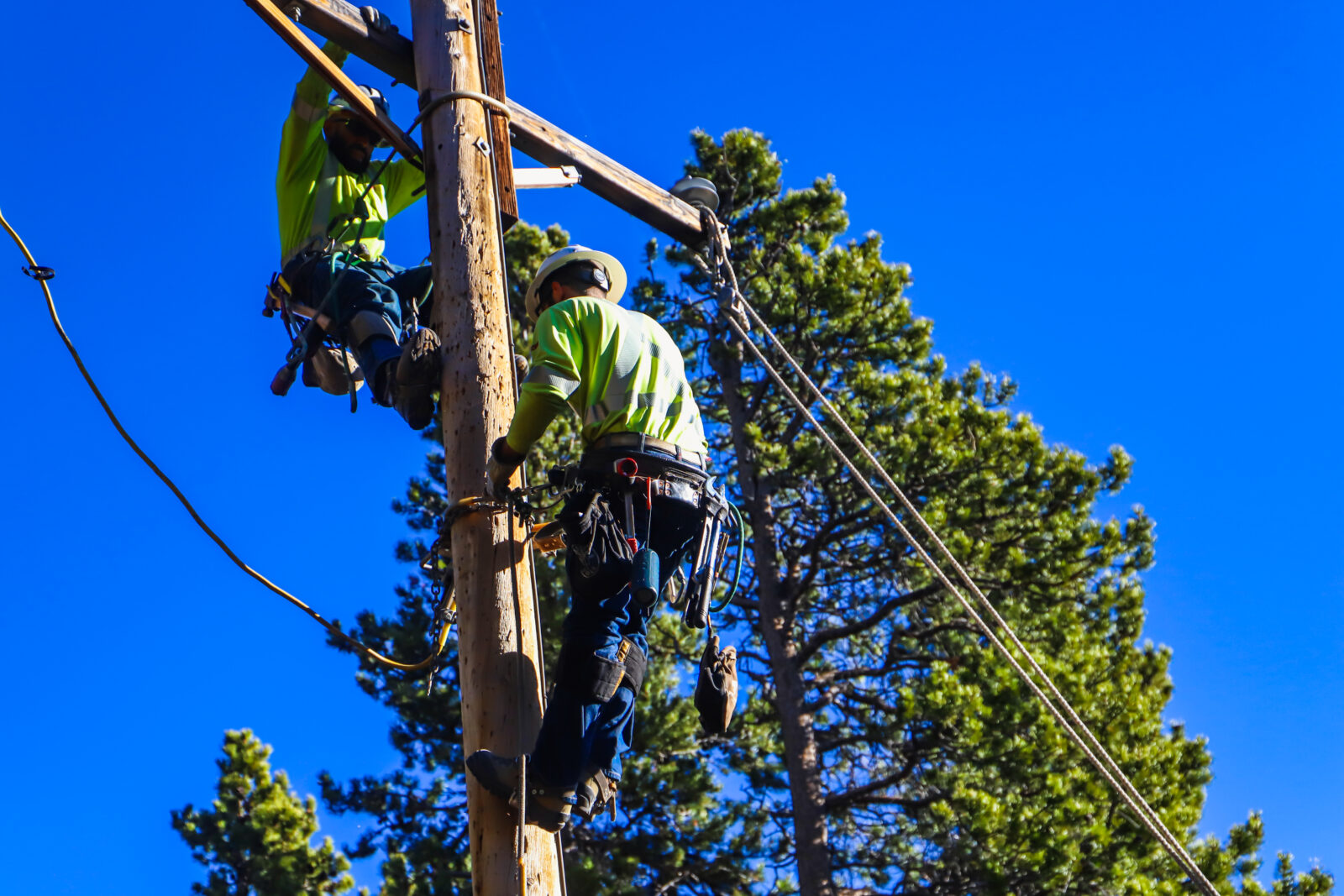 Two linemen work on an electric line.